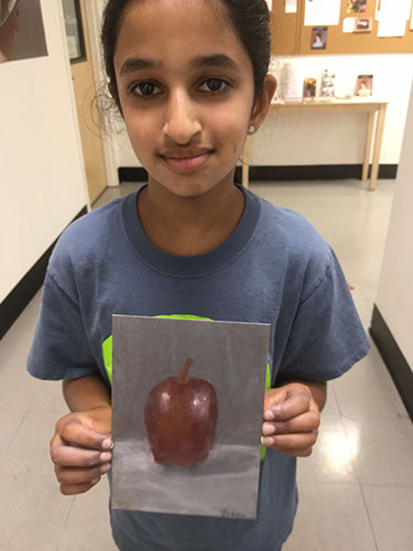 Young girl holding her realistic painting of a red apple