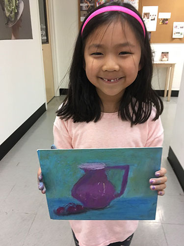 Young girl holding her painting of purple pitcher with fruit